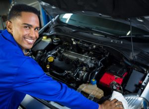 Portrait of happy mechanic servicing car at repair garage